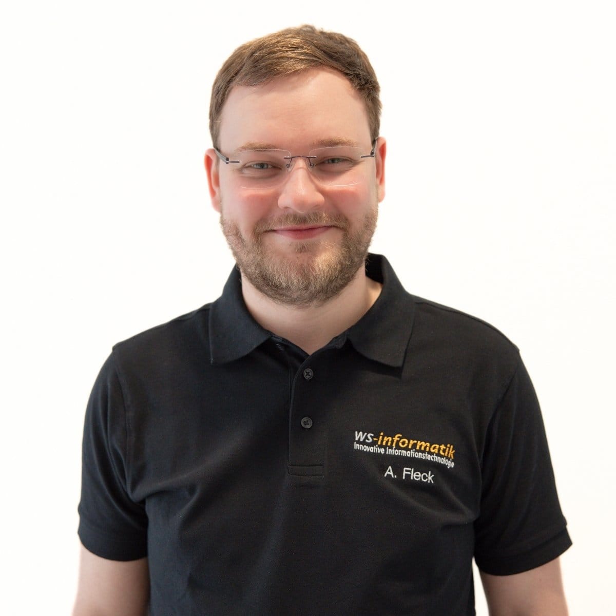 Portrait von Alexander, Servicetechniker bei der WS-Informatik GmbH & Co. KG, im schwarzen Poloshirt mit Firmenlogo, vor weißem Hintergrund.
