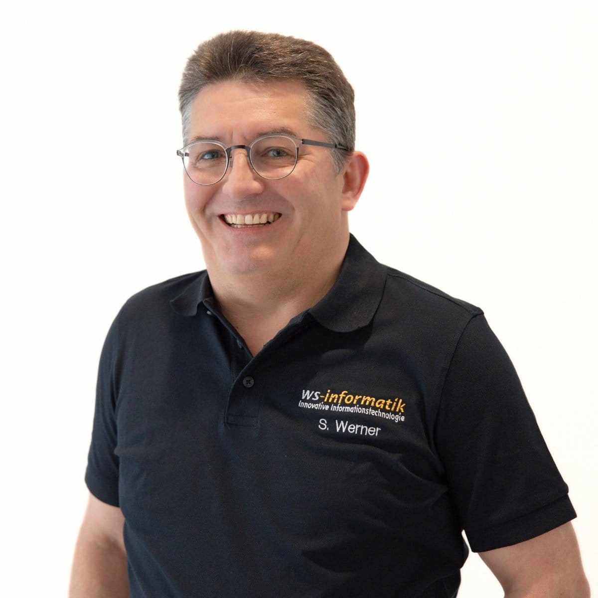Portrait von Dr. Stephan Werner, Geschäftsführer der WS-Informatik GmbH & Co. KG, im schwarzen Poloshirt mit Firmenlogo, vor weißem Hintergrund.