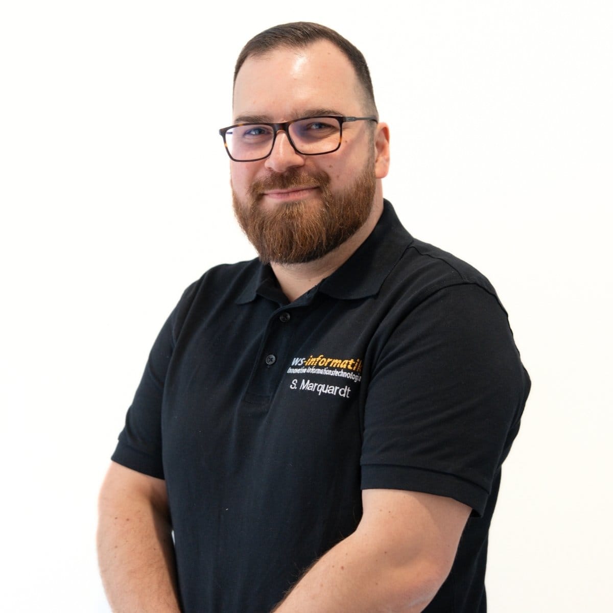 Portrait von Sven, Servicetechniker bei der WS-Informatik GmbH & Co. KG, im schwarzen Poloshirt mit Firmenlogo, vor weißem Hintergrund