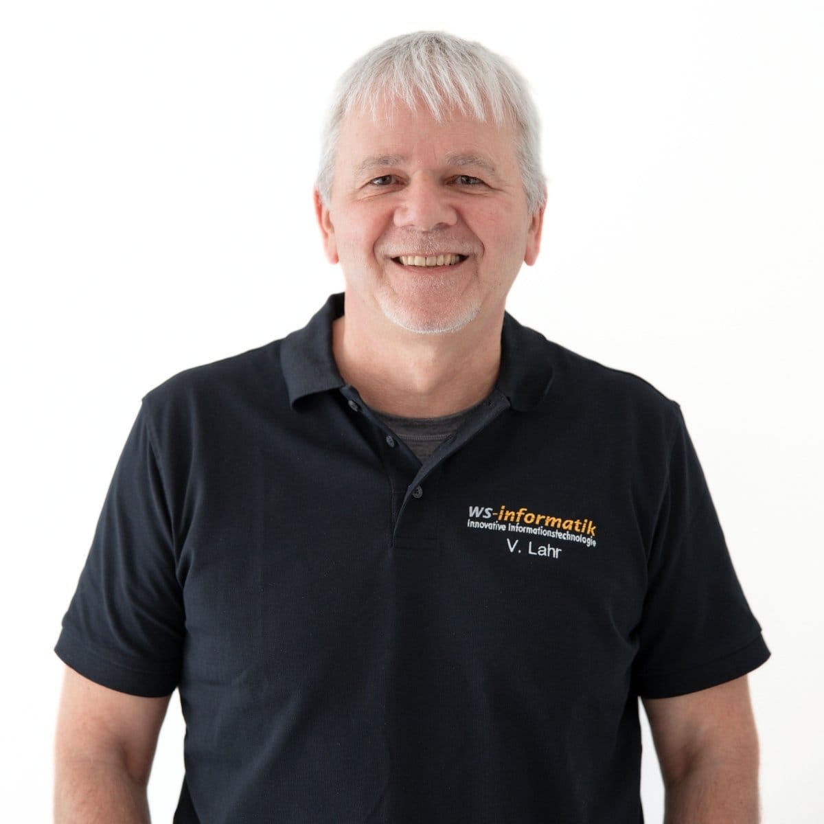 Portrait von Volker, Systemberater bei der WS-Informatik GmbH & Co. KG, im schwarzen Poloshirt mit Firmenlogo, vor weißem Hintergrund.
