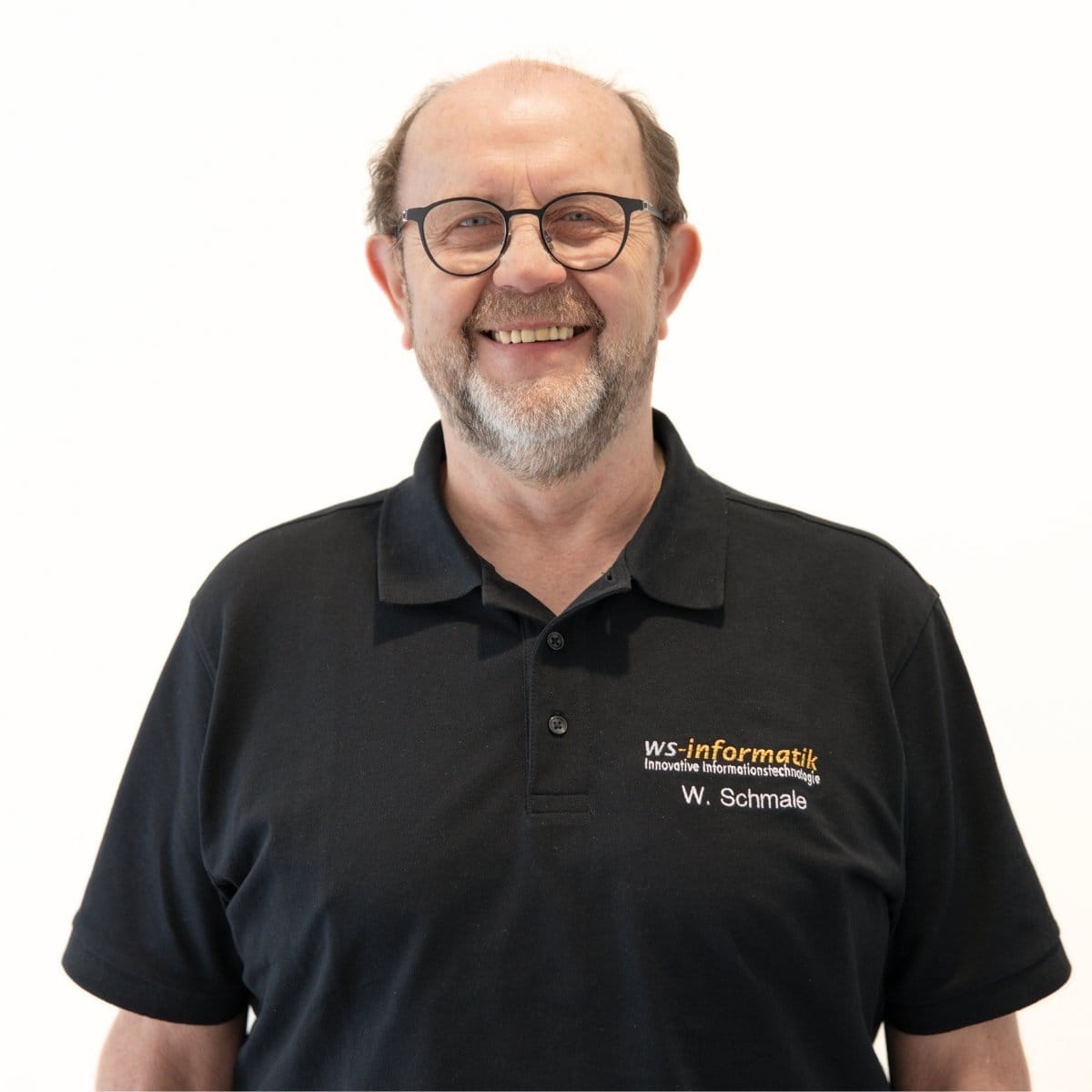 Portrait von Walter, Systemberater für Telekommunikation bei der WS-Informatik GmbH & Co. KG, im schwarzen Poloshirt mit Firmenlogo, vor weißem Hintergrund